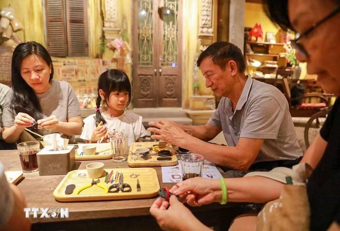 Khách tham quan trải nghiệm làm dép lốp. (Ảnh: Khánh Hoà/TTXVN)