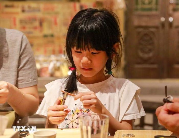 Khách tham quan trải nghiệm làm dép lốp. (Ảnh: Khánh Hoà/TTXVN)