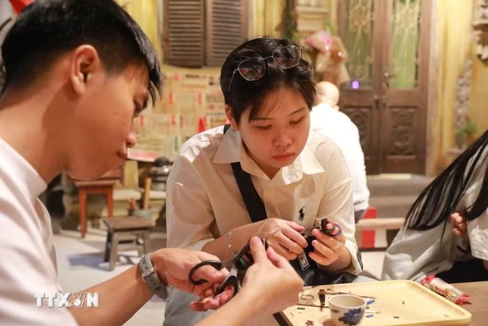 Khách tham quan trải nghiệm làm dép lốp. (Ảnh: Khánh Hoà/TTXVN)