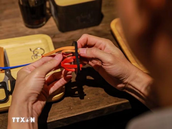 Khách tham quan trải nghiệm làm dép lốp. (Ảnh: Khánh Hoà/TTXVN)