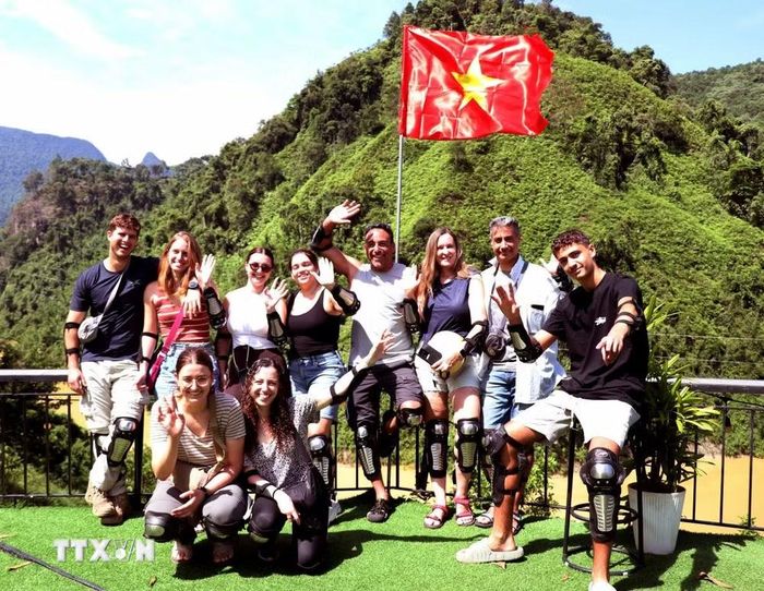 Du khách nước ngoài chụp những tấm ảnh lưu niệm dưới lá cờ đỏ sao vàng trong dịp lễ Quốc khánh 2/9. (Ảnh: Đức Thọ/TTXVN)