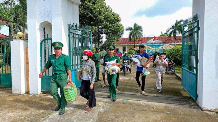 Các chiến sĩ biên phòng hỗ trợ người dân mang các phần quà về nhà. Ảnh: TTXVN phát