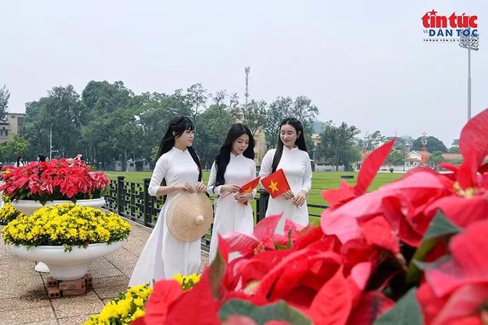 Các bạn trẻ trong tà áo dài trắng, tay cầm cờ Tổ quốc tại Quảng trường Ba Đình.