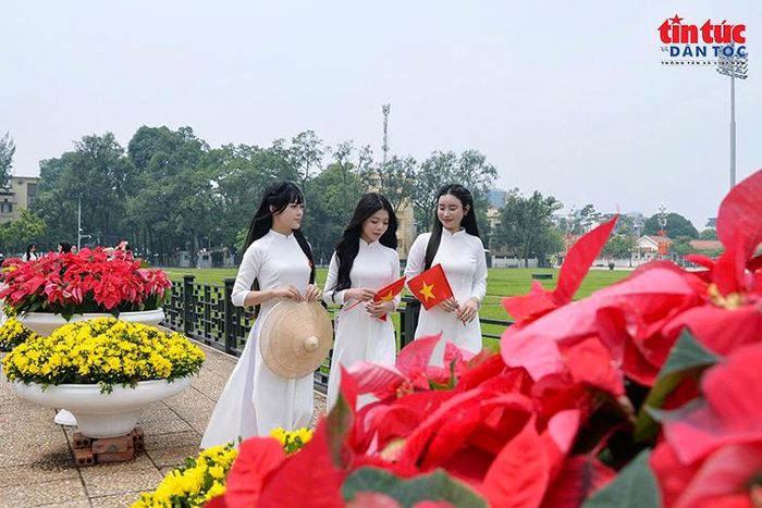 Các bạn trẻ trong tà áo dài trắng, tay cầm cờ Tổ quốc tại Quảng trường Ba Đình.