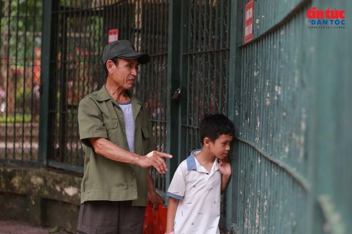 Ông Lợi cùng cháu đang chỉ cho cháu về các con vật tại sở thú.