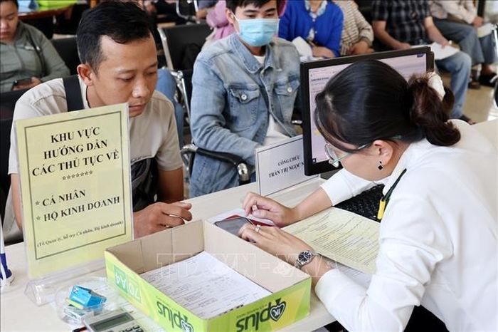 Cán bộ Thuế cơ sở 7 (Thuế An Giang) hướng dẫn người dân thủ tục thuế. Ảnh: Phạm Hậu/TTXVN