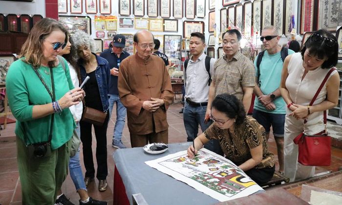 Khách quốc tế tham quan tìm hiểu nghề làm tranh dân gian Đông Hồ tại gia đình Nghệ nhân Nguyễn Hữu Hoa (tổ dân phố Đông Hồ, phường Thuận Thành).