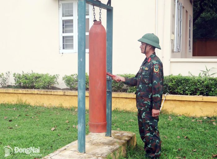 Cán bộ trực ban gõ kẻng báo động tình huống giả định chữa cháy, dập lửa tại khu kỹ thuật đơn vị. Ảnh: Nguyệt Hà