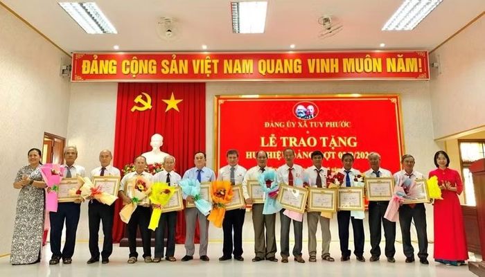  Lãnh đạo Đảng ủy xã Tuy Phước trao huy hiệu Đảng cho các đảng viên. Ảnh: Thùy Duyên 