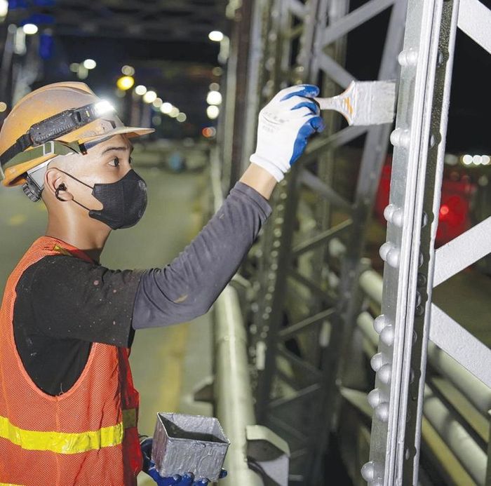 Công nhân chăm chú sơn lên từng cấu kiện thép của vòm cầu.