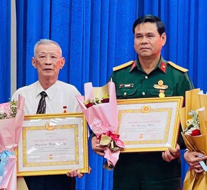 CCB Đại tá Lê Quang Hồi (bên phải) nhân Huy hiệu 35 năm tuổi Đảng.↵