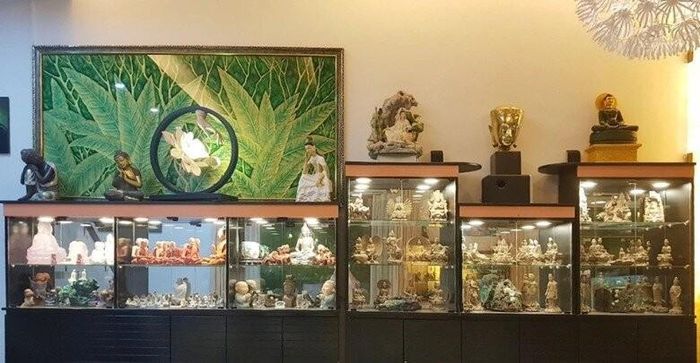 Cận cảnh hệ thống tủ kính đồ sộ trưng bày hàng trăm bức tượng Phật, tượng Bồ Tát với đa dạng chất liệu, kích thước được gia chủ bài trí vô cùng trang nghiêm. Không gian phía trên còn được tô điểm bởi bức tranh lá xanh tươi mát cùng đèn trang trí hình hoa sen tinh tế, tạo nên bầu không khí thanh tịnh và ấm cúng cho ngôi nhà.