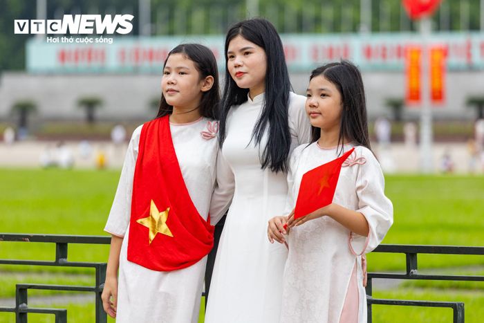 Người phụ nữ và 2 con gái lựa chọn áo dài trắng, kết hợp cùng cờ Tổ quốc để ghi lại khoảnh khắc ý nghĩa trước thềm ngày lễ lớn.