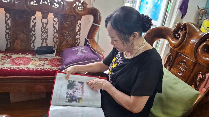 Bà Phạm Thị Huyền xem lại bức ảnh chụp các học trò lứa đầu tiên của lớp học tình thương. Ảnh: Hiền Chi