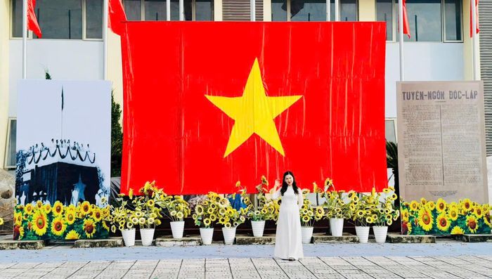 Du khách check-in dưới lá cờ Tổ quốc cỡ lớn được trang trí nổi bật tại Không gian văn hóa Việt Hưng. Ảnh: PV