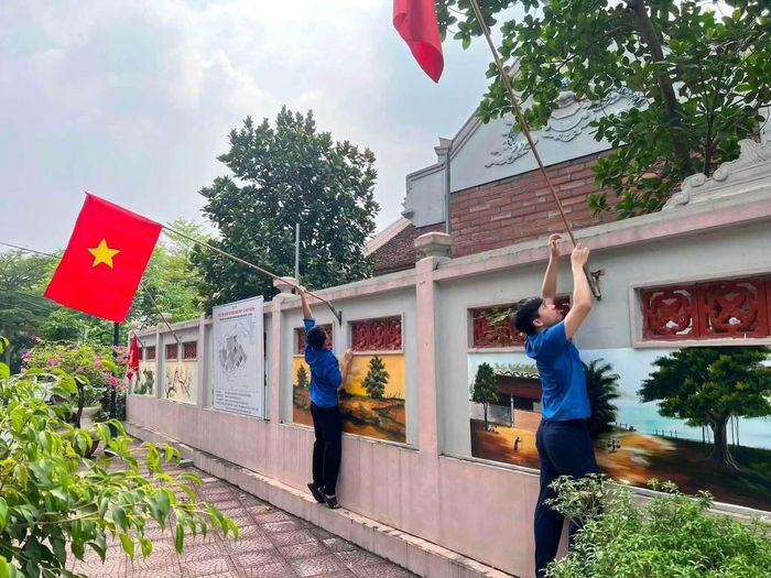Đoàn viên thanh niên xã Đan Phượng treo cờ Tổ quốc trên các tuyến đường. Ảnh: ĐP
