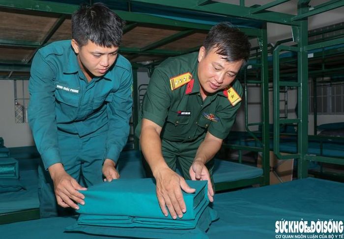 Thượng tá Nguyễn Thành Chơn, Chỉ huy trưởng Ban CHQS phường Ba Ngòi hướng dẫn Phong xếp nội vụ. Ảnh: Duy Ngọc.