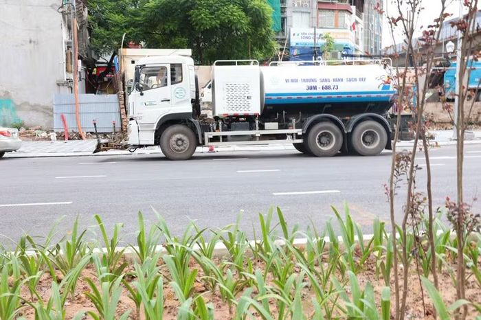 Xe bồn chuyên dụng liên tục phun nước rửa bụi bẩn, làm sạch bề mặt thảm nhựa mới trên toàn tuyến.