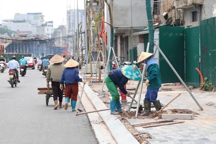 Tổ công nhân tất bật vận chuyển đất màu, chỉnh sửa bồn cây và hoàn thiện lát đá vỉa hè trước những ngôi nhà vừa lùi sâu vào sau giải phóng mặt bằng.