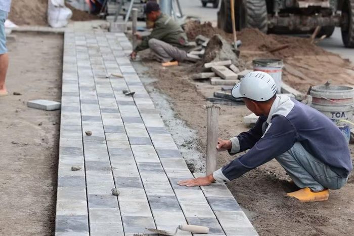 Người thợ xây dựng tỉ mỉ đặt từng viên gạch lát vỉa hè theo đường dây rọi, chạy đua tiến độ bàn giao trước dịp Quốc khánh 2/9.