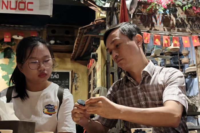 Phó Chủ tịch UBND phường Ba Đình Nguyễn Dân Huy trực tiếp hướng dẫn du khách trẻ kỹ thuật đục và xỏ quai dép lốp cao su.