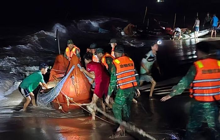 Lực lượng chức năng cùng ngư dân kéo thuyền bị sóng cuốn trôi vào bờ tại thôn Mỹ Thủy, xã Mỹ Thủy, tỉnh Quảng Trị. (Ảnh: H.M)