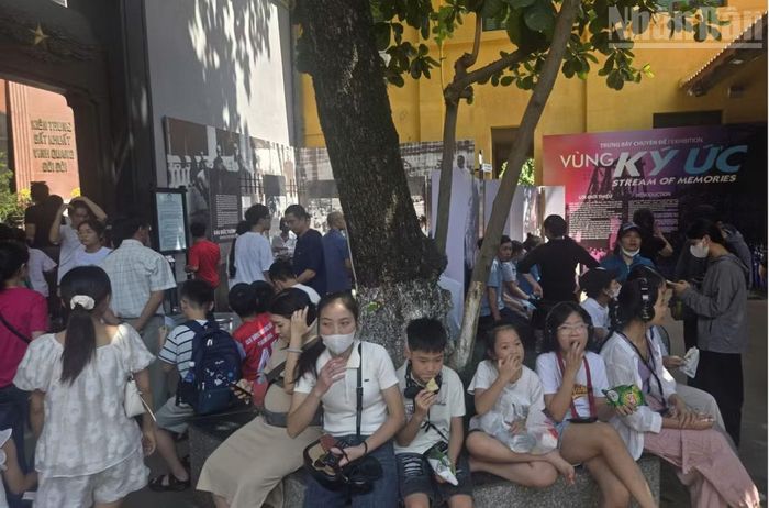Khu vực chờ nghỉ bên trong di tích không còn chỗ trống khiến nhiều du khách tận dụng ngồi nghỉ cả bên gốc cây.