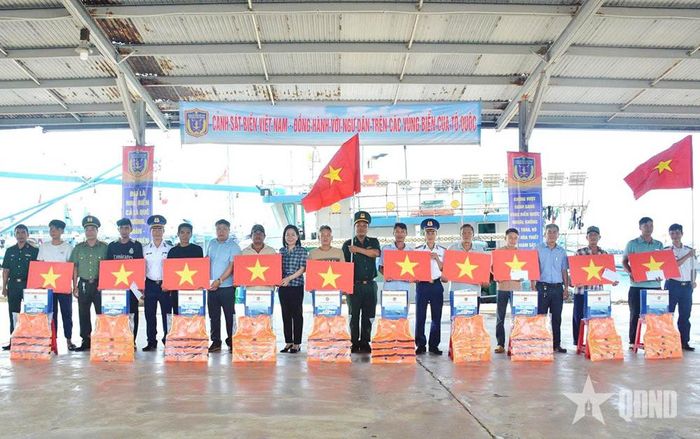 Đại diện Vùng Cảnh sát biển 3 phối hợp trao cờ Tổ quốc, áo phao và quà tặng ngư dân. 