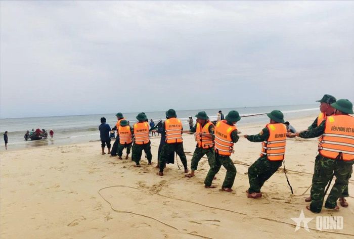 Cán bộ, chiến sĩ Đồn Biên phòng cửa khẩu cảng Cửa Việt (Ban chỉ huy BĐBP tỉnh Quảng Trị) hỗ trợ ngư dân xã Cửa Việt kéo thuyền bị chìm vào bờ. Ảnh: HOÀI NAM