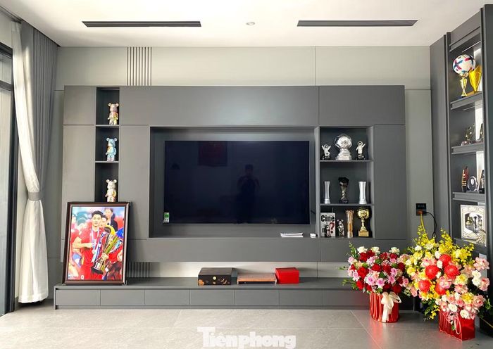Không gian phòng khách được bố trí nhiều kệ, tủ để trưng bày cúp, huy chương và những kỷ vật gắn với hành trình thi đấu của Đình Bắc. Những thành tích trên sân cỏ vì thế được đưa về gần hơn với cuộc sống gia đình, trở thành niềm vui và niềm tự hào của bố mẹ anh.