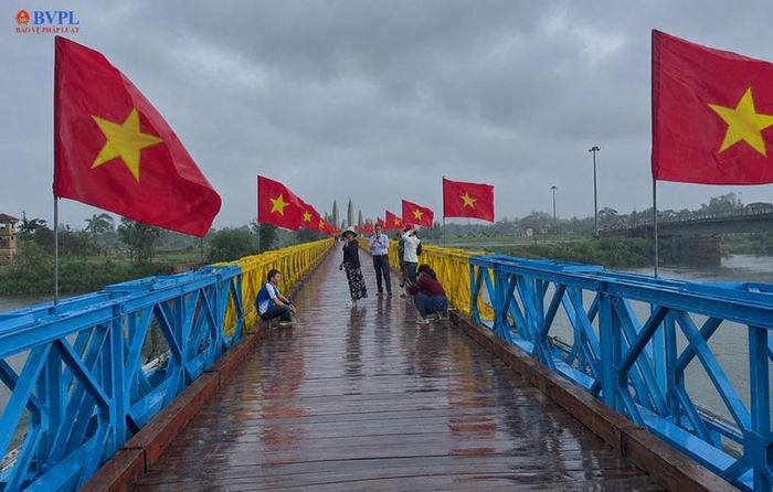 Rất nhiều du khách chụp ảnh kỷ niệm trên mặt cầu dưới mưa.