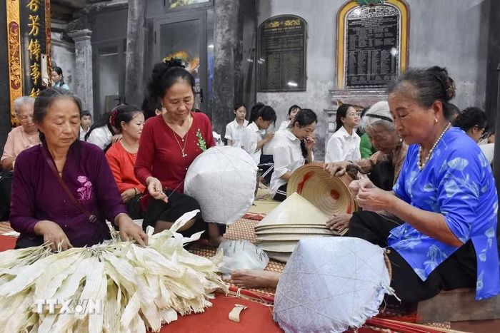 Các nghệ nhân làng Chuông trình diễn nghề làm nón truyền thống. (Ảnh: Nguyễn Cúc/TTXVN)