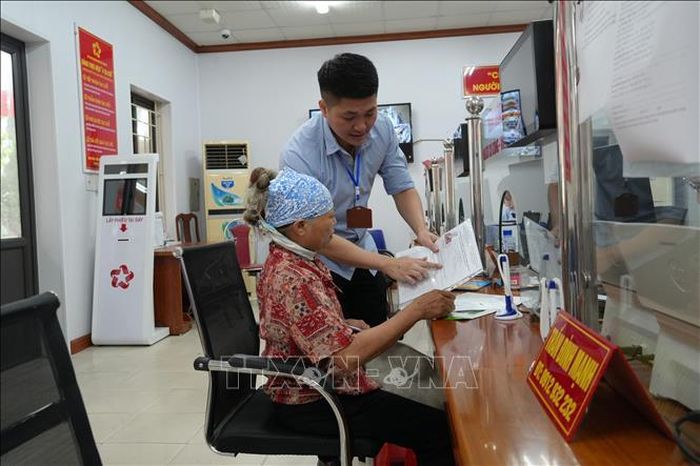 Ông Phạm Quang Huy, Phó Giám đốc Trung tâm Phục vụ hành chính công xã Yên Mỹ hướng dẫn người dân kê khai, nộp hồ sơ. Ảnh: Mạnh Khánh/TTXVN