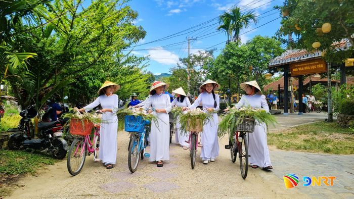 Những cô gái trong tà áo dài duyên dáng chụp ảnh lưu niệm với xe hoa mo cau tại Lộc Yên. Ảnh: D.LỆ