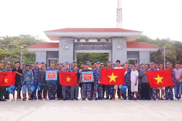 Cán bộ, chiến sĩ đảo Trường Sa tặng cờ Tổ quốc và nhu yếu phẩm cho ngư dân trước khi lên tàu.