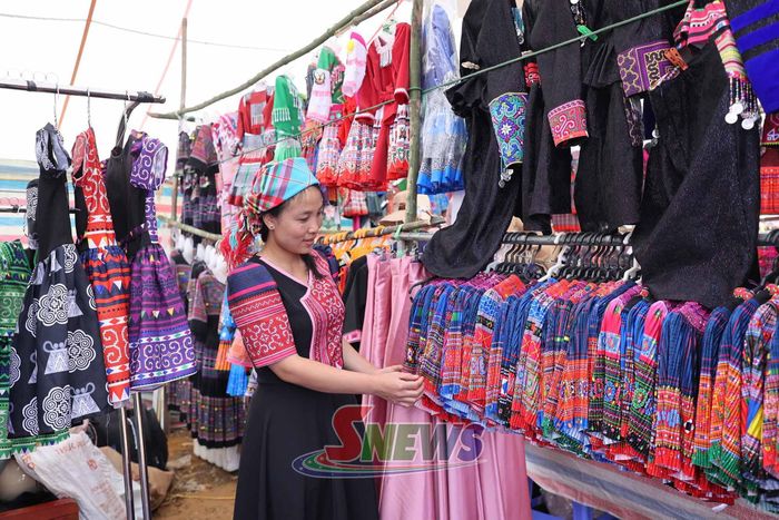 Du khách mua sắm tại gian hàng bán trang phục thổ cẩm.