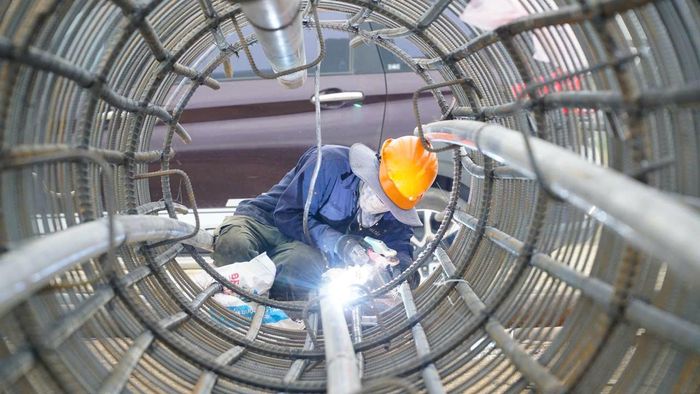 Giữa công trường ngổn ngang máy móc, anh Nguyễn Thành Tài (42 tuổi, quê Quảng Nam) vẫn miệt mài với phần việc hàn chốt định vị lồng cọc phục vụ thi công cọc khoan nhồi.