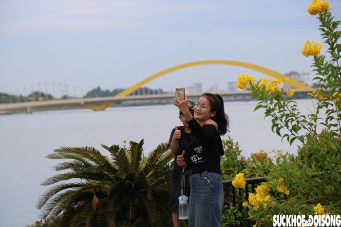 Không chỉ chụp ảnh hướng về chùa Thiên Mụ, du khách còn tranh thủ lưu lại những khoảnh khắc bên sông Hương với khung cảnh phía sau là cây cầu Nguyễn Hoàng. Ảnh: H.D.