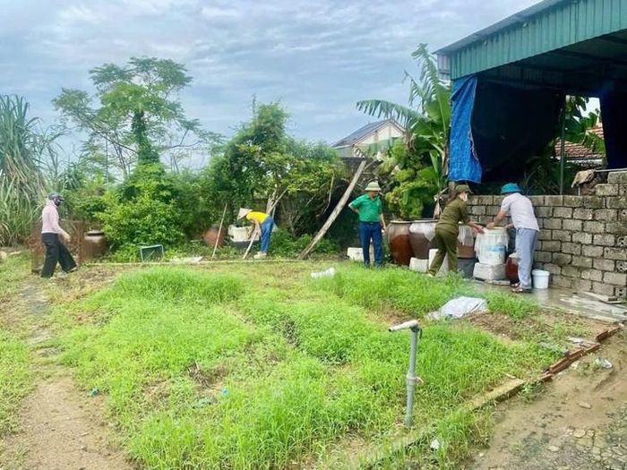 Lực lượng chức năng và người dân tại xã Quỳnh Anh thu gom phế thải, xử lý các dụng cụ chứa nước nhằm loại bỏ nơi sinh sản của muỗi truyền bệnh sốt xuất huyết. Ảnh: Q.A