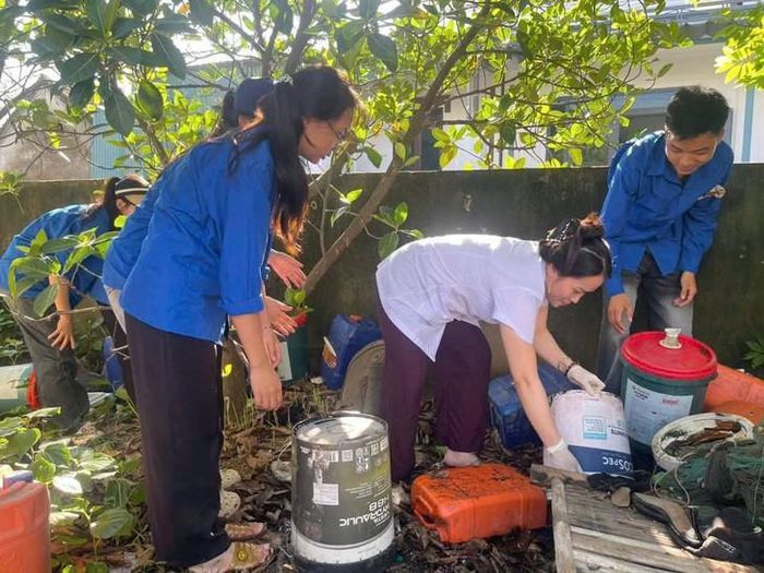 Lực lượng chức năng và người dân xã Quỳnh Anh vệ sinh môi trường, thu gom các vật dụng có nguy cơ chứa nước, loại bỏ nơi sinh sản của muỗi truyền bệnh sốt xuất huyết. ẢNH: Q.A