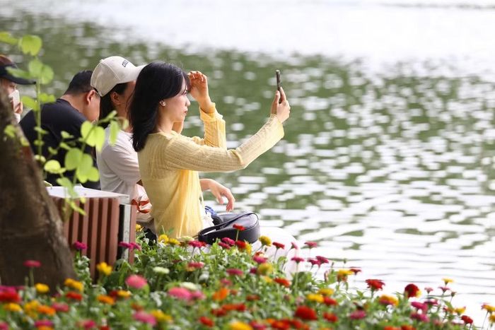 Người dân tranh thủ chụp ảnh, lưu giữ khoảnh khắc bên các thảm hoa trong chuyến dạo Hồ Gươm dịp lễ
