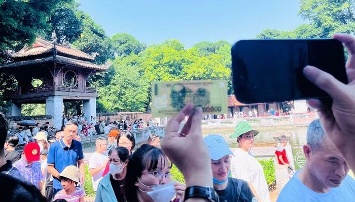 Cách "check-in" độc đáo của du khách khi chụp tờ tiền mệnh giá 100.000 đồng có in hình Khuê Văn Các chung một khuôn hình với Khuê Văn Các ngoài đời thực