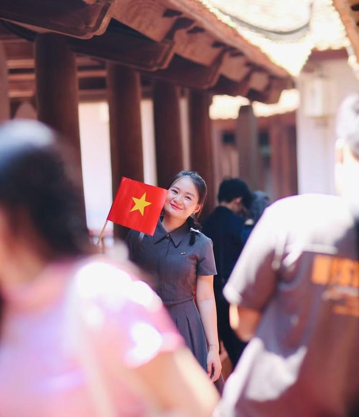 Nữ du khách mang theo lá cờ Tổ quốc chụp ảnh lưu niệm bên các bia tiến sỹ