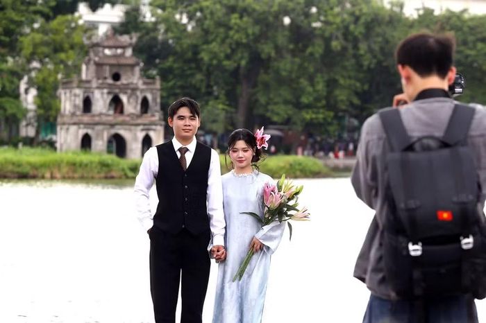 Đôi bạn trẻ tranh thủ chụp ảnh bên Hồ Gươm, ghi dấu một ngày nghỉ lễ đáng nhớ.