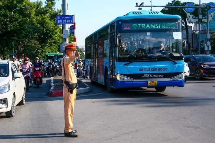 Cảnh sát giao thông ra hiệu lệnh dẫn dòng, tạo lối đi an toàn cho xe buýt vận tải hành khách công cộng và người điều khiển xe máy di chuyển nhịp nhàng.