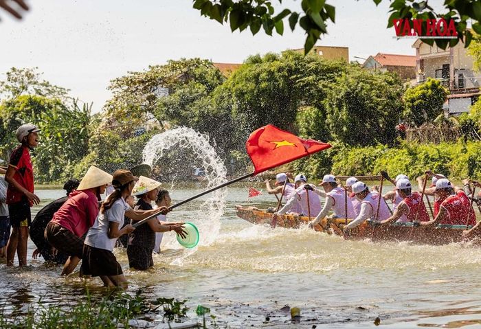 Người dân xuống tận mép nước, phất cờ, vẫy nón, hắt nước tiếp sức cho đội thuyền đang rướn mình vượt lên