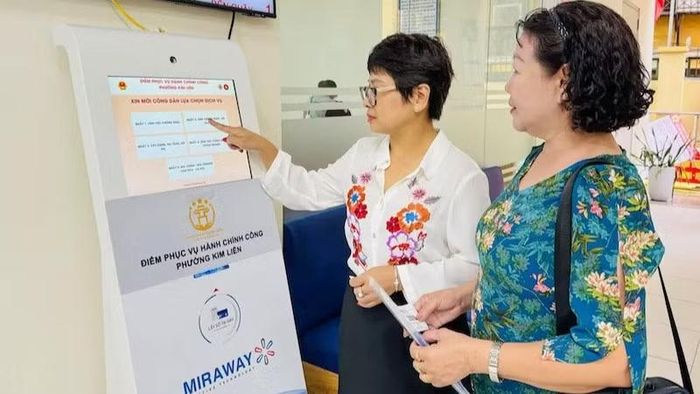 Công chức tại Điểm tiếp nhận, phục vụ hành chính công phường Kim Liên hướng dẫn người dân lấy số để thực hiện các thủ tục hành chính. (Ảnh: KHÁNH HUY)