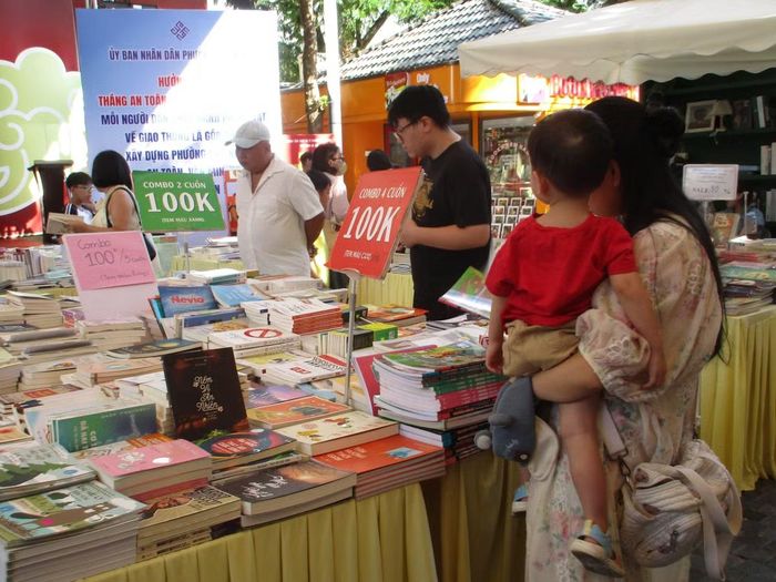 Nhiều em nhỏ cùng cha mẹ hào hứng dừng chân rất lâu tại các gian hàng sách thiếu nhi để tự tay tìm kiếm, đọc thử và chọn lựa những cuốn sách. (Ảnh: Bảo Châu)