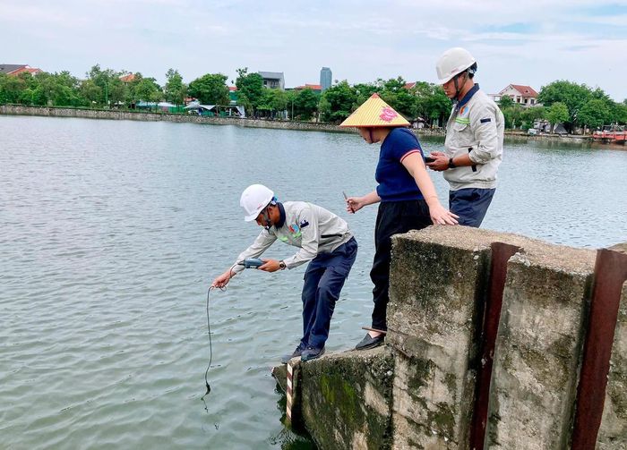 Cơ quan chức năng lấy mẫu nước để xác định nguyên nhân cá chết. Ảnh: Đình Việt