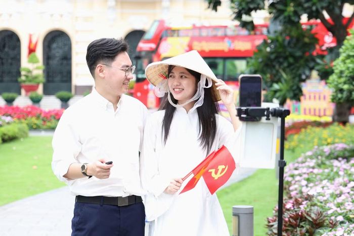 Đôi bạn trẻ mang theo cờ Tổ quốc chụp ảnh trước tòa nhà UBND TPHCM.
